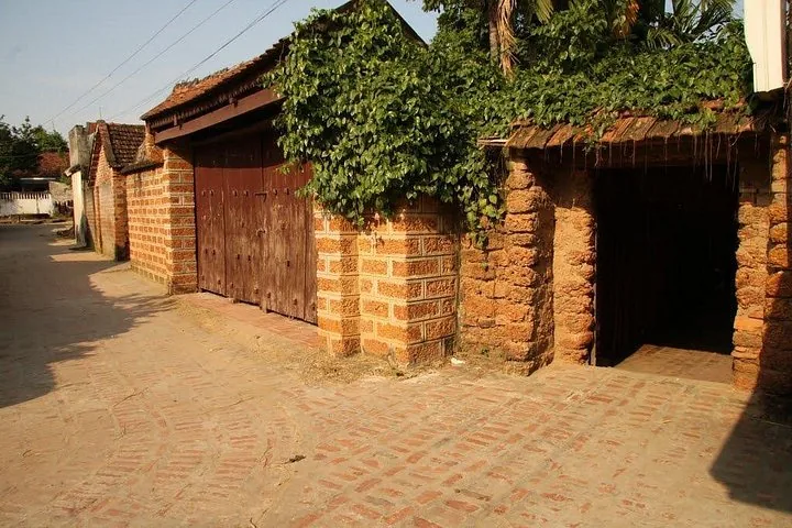 Una calle tranquila de un pueblo con paredes de ladrillo, puertas de madera y hiedra.